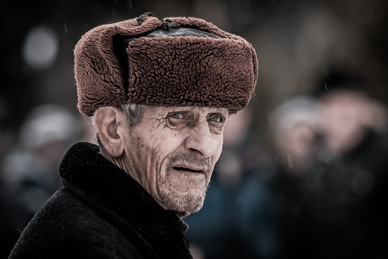 un vieil homme russe montrant comment porter son chapka correctement